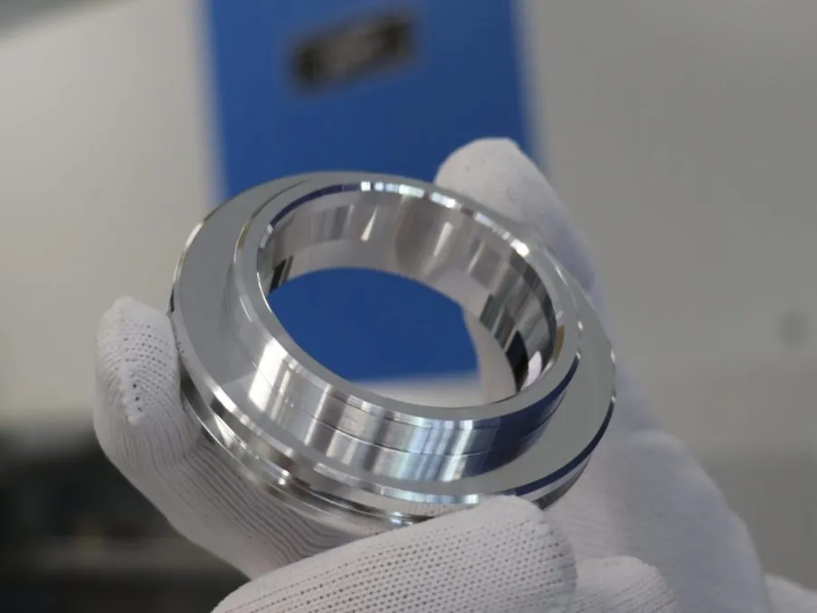 Quality inspector handling a finished machined brass ring during final inspection at Brassland